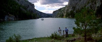 Movie still from “Thunderbolt and Lightfoot” (1974), directed by Michael Cimino – Two people standing on the side of a river looking at a boat; Extreme Wide shot, High angle