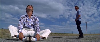 Movie still from “Thunderbolt and Lightfoot” (1974), directed by Michael Cimino – A man sitting on the ground with his head down; Medium shot, Low angle