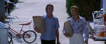 Movie still from “Thunderbolt and Lightfoot” (1974), directed by Michael Cimino – Two men walking down the street holding paper bags; Medium shot, Low angle