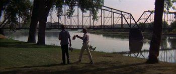 Movie still from “Thunderbolt and Lightfoot” (1974), directed by Michael Cimino – Two people standing next to each other near a body of water; Wide shot, Over the shoulder angle
