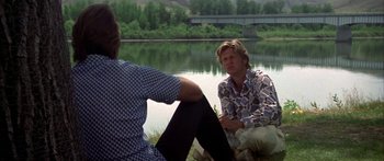 Movie still from “Thunderbolt and Lightfoot” (1974), directed by Michael Cimino – A man and a woman sitting next to a body of water; Medium shot, Over the shoulder angle