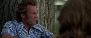 Movie still from “Thunderbolt and Lightfoot” (1974), directed by Michael Cimino – A person sitting in front of a tree; Close Up shot, Over the shoulder angle