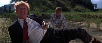 Movie still from “Thunderbolt and Lightfoot” (1974), directed by Michael Cimino – A man sitting on the ground with a camera in his hand and another man sitting on the ground; Medium shot, Low angle