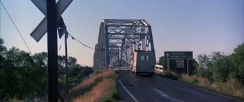 Movie still from “Thunderbolt and Lightfoot” (1974), directed by Michael Cimino – A bus driving on a road under a bridge; Extreme Wide shot, Low angle