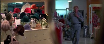 Movie still from “Thunderbolt and Lightfoot” (1974), directed by Michael Cimino – A man walks through a clothing store filled with lots of hats; Medium shot, Over the shoulder angle