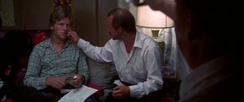 Movie still from “Thunderbolt and Lightfoot” (1974), directed by Michael Cimino – A man sitting at a table with papers in front of him; Close Up shot, Over the shoulder angle