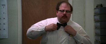 Movie still from “Thunderbolt and Lightfoot” (1974), directed by Michael Cimino – A man with a beard and glasses tying a bow tie; Medium shot, Low angle