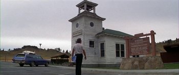 Movie still from “Thunderbolt and Lightfoot” (1974), directed by Michael Cimino – A person walking in front of a building with a clock tower; Wide shot, Low angle