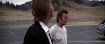 Movie still from “Thunderbolt and Lightfoot” (1974), directed by Michael Cimino – Two men standing next to each other on the side of a road; Medium shot, Over the shoulder angle