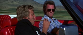 Movie still from “Thunderbolt and Lightfoot” (1974), directed by Michael Cimino – Two men sitting on a red couch with a cigar in their mouth; Medium shot, Low angle