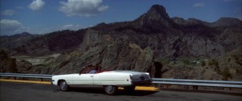 Movie still from “Thunderbolt and Lightfoot” (1974), directed by Michael Cimino – A man riding in the back of a white convertible car; Extreme Wide shot, High angle