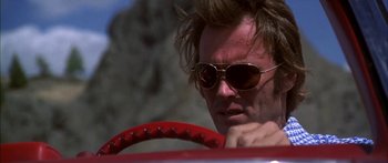 Movie still from “Thunderbolt and Lightfoot” (1974), directed by Michael Cimino – A man in sunglasses sitting in a red car; Close Up shot, Low angle