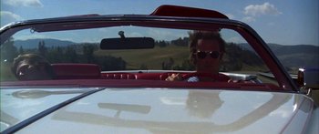 Movie still from “Thunderbolt and Lightfoot” (1974), directed by Michael Cimino – A man driving a red car in the middle of the road; Medium shot, Low angle