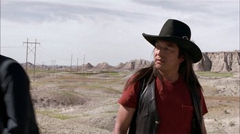 Movie still from “Thunderheart” (1992), directed by Michael Apted – A man with long hair wearing a cowboy hat; Medium shot, Over the shoulder angle