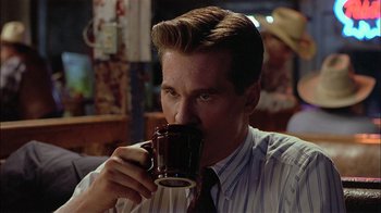 Movie still from “Thunderheart” (1992), directed by Michael Apted – A person holding a cup of coffee; Close Up shot, Over the shoulder angle