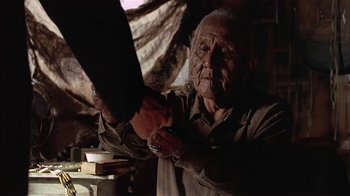 Movie still from “Thunderheart” (1992), directed by Michael Apted – An old man is holding a pair of scissors in his hand; Close Up shot, Over the shoulder angle