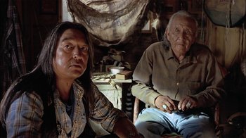 Movie still from “Thunderheart” (1992), directed by Michael Apted – A man sitting next to an older man in a chair; Close Up shot, Over the shoulder angle