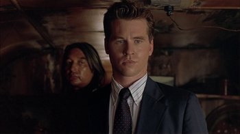 Movie still from “Thunderheart” (1992), directed by Michael Apted – A man in a suit and tie standing next to another man in a suit; Close Up shot, Low angle