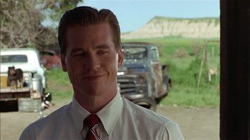 Movie still from “Thunderheart” (1992), directed by Michael Apted – A man wearing a white dress shirt and red tie standing in front of an old truck; Close Up shot, Low angle