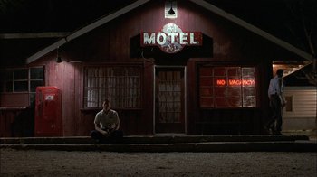 Movie still from “Thunderheart” (1992), directed by Michael Apted – A man sitting in front of an old motel; Wide shot, Low angle