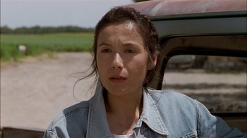 Movie still from “Thunderheart” (1992), directed by Michael Apted – A woman in a denim jacket standing in front of a car; Close Up shot, Over the shoulder angle