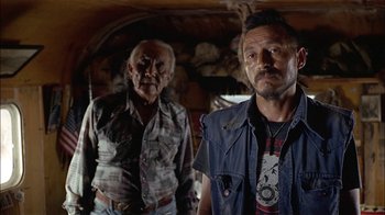 Movie still from “Thunderheart” (1992), directed by Michael Apted – Two men standing next to each other in front of a wall; Medium shot, Over the shoulder angle