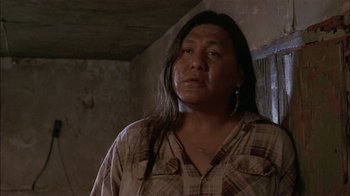 Movie still from “Thunderheart” (1992), directed by Michael Apted – A person standing in a room looking at the camera; Close Up shot, Low angle