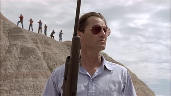 Movie still from “Thunderheart” (1992), directed by Michael Apted – A man with a rifle standing on top of a hill; Medium shot, Low angle
