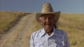 Movie still from “Thunderheart” (1992), directed by Michael Apted – An old man wearing a hat standing on a dirt road; Close Up shot, Low angle