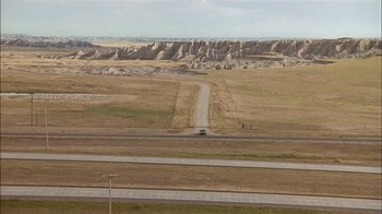 Movie still from “Thunderheart” (1992), directed by Michael Apted – A car driving down a road in the middle of a field; Extreme Wide shot, High angle