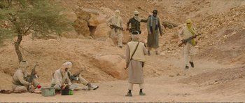 Movie still from “Timbuktu” (2014), directed by Abderrahmane Sissako – A group of men standing on top of a dirt hill; Wide shot, High angle