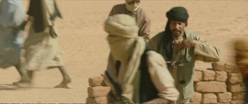 Movie still from “Timbuktu” (2014), directed by Abderrahmane Sissako – Two men sitting on a pile of rocks in the desert; Medium shot, Over the shoulder angle