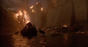 Movie still from “Time Bandits” (1981), directed by Terry Gilliam – A man in a boat on a body of water; Extreme Wide shot, High angle