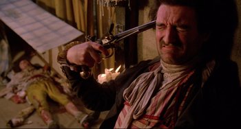 Movie still from “Time Bandits” (1981), directed by Terry Gilliam – A man holding a gun up to his face; Close Up shot, High angle
