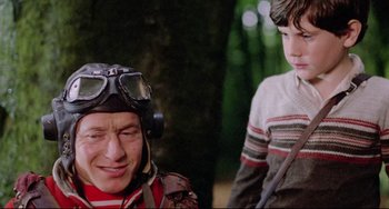 Movie still from “Time Bandits” (1981), directed by Terry Gilliam – A man wearing a helmet and goggles next to a boy; Medium shot, Over the shoulder angle