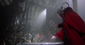 Movie still from “Time Bandits” (1981), directed by Terry Gilliam – A woman in a red suit is looking into the water; Wide shot, High angle