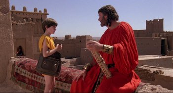 Movie still from “Time Bandits” (1981), directed by Terry Gilliam – A man in a red robe talking to a boy in a yellow shirt; Medium shot, Over the shoulder angle