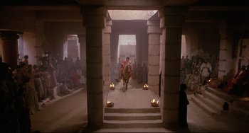 Movie still from “Time Bandits” (1981), directed by Terry Gilliam – A man in a red robe walking through a building with candles; Extreme Wide shot, Low angle