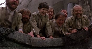 Movie still from “Time Bandits” (1981), directed by Terry Gilliam – A group of people laughing and playing with a barrel; Medium shot, High angle