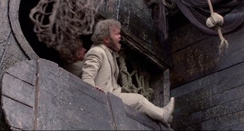 Movie still from “Time Bandits” (1981), directed by Terry Gilliam – A man sitting on top of a wooden structure; Wide shot, Low angle