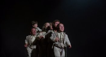 Movie still from “Time Bandits” (1981), directed by Terry Gilliam – A group of young men in white suits singing in the dark; Wide shot, Low angle