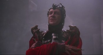 Movie still from “Time Bandits” (1981), directed by Terry Gilliam – A man in a red and black suit and a metal helmet; Close Up shot, Low angle