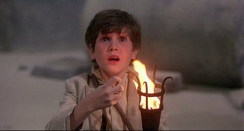 Movie still from “Time Bandits” (1981), directed by Terry Gilliam – A young boy is holding a burning candle; Close Up shot, Low angle