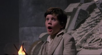 Movie still from “Time Bandits” (1981), directed by Terry Gilliam – A young boy in a suit is looking surprised; Close Up shot, Low angle