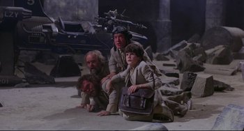 Movie still from “Time Bandits” (1981), directed by Terry Gilliam – A group of people sitting on the ground in a room; Wide shot, High angle