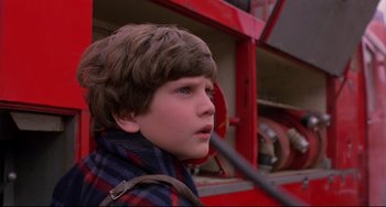 A young boy standing in front of a fire truck
