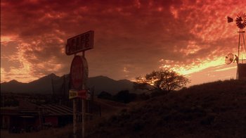 Movie still from “Tin Cup” (1996), directed by Ron Shelton – A red sky with clouds and a sign in the foreground; Extreme Wide shot, Low angle