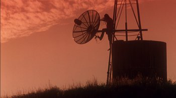 Movie still from “Tin Cup” (1996), directed by Ron Shelton – A man standing on top of a tower next to a satellite dish; Extreme Wide shot, Low angle