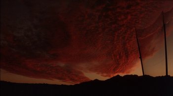 Movie still from “Tin Cup” (1996), directed by Ron Shelton – The sky is red and dark with a lot of clouds; Extreme Wide shot, Low angle