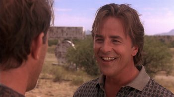 Movie still from “Tin Cup” (1996), directed by Ron Shelton – A man with long hair is smiling at another man; Close Up shot, Over the shoulder angle